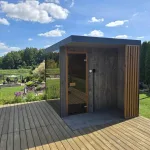 Sauna ogrodowa z panoramicznym przeszkleniem na drewnianym tarasie